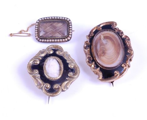 Three Victorian mourning brooches, consisting of a yellow metal scrollwork brooch inlaid with black enamel with hair panel se
