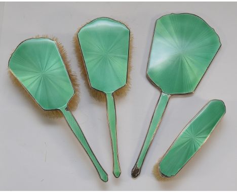 A silver and green guilloche enamel four piece dressing table set, Birmingham 1932, compromising a hand mirror, two hair brus