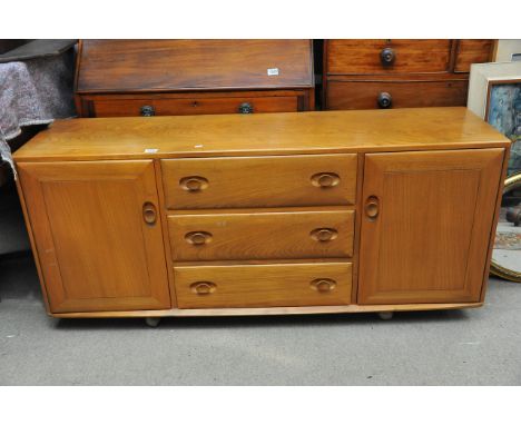 A light elm Ercol sideboard fitted with three drawers flanked by two cupboard doors, approx 155cm x 68cm x 44cm.