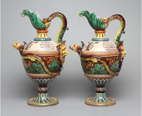 A PAIR OF MAIOLICA PEDESTAL EWERS, c.1900, of ovoid form with acanthus lip, bi-furcated snake's head loop handle with male gr