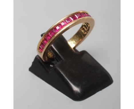 A RUBY HALF HOOP ETERNITY RING, the eighteen square cut stones channel set to a plain shank stamped 14k, size J (Est. plus 24