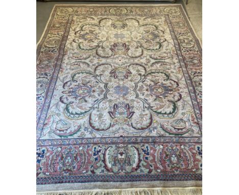 AN INDIAN WOOL CARPET, modern, in the Persian style, the ivory field with repeating scrolling foliate pattern in shades of gr