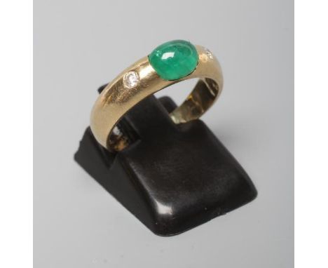 AN EMERALD AND DIAMOND RING, the oval cabochon polished emerald tension set and flanked by two gypsy set small diamonds to a 