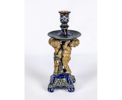 A STONEWARE FIGURAL CANDLESTICK, probably designed by George Tinworth for Doulton Lambeth, the reel socket issuing from a wid
