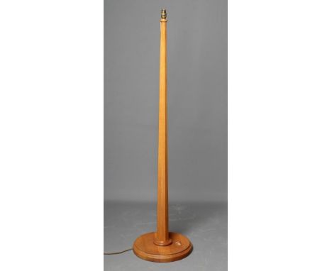 AN OAK STANDARD LAMP BY GEOFF GELL OF COXWOLD, the tapering faceted stem on on moulded edged dished circular base, carved uni