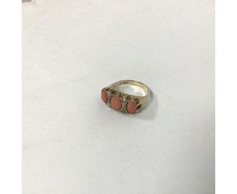 A 9ct gold dress ring mounted oval polished coral flanked by a coral oval cut stone to each shoulder with two rows of seed pe