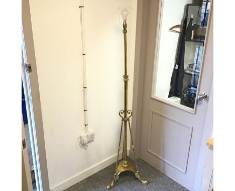 A brass floor lamp, the cylindrical stem supported by three curved supports terminating in a tripod base with moulded feet (h