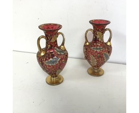 A pair of Bohemian cranberry glass bud vases, c.1900, of amphora form with flared rims, with gilt handles and applied gilt an