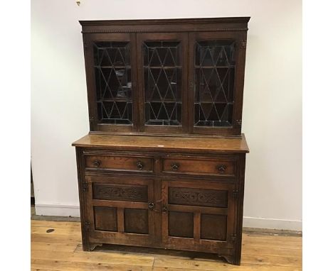 An Ercol style oak dresser, the raised back with hobnail detail and three leaded glazed doors enclosing three shelves, the ba