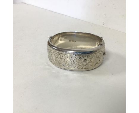 A 1960s Birmingham silver bangle with engraved foliate decoration to one half (h.2cm x 6.5 x 5.5) (38.82g)