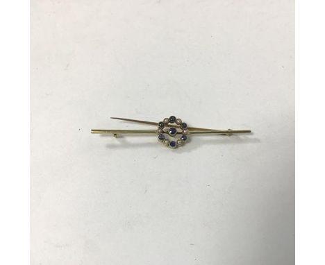 A 15ct gold bar brooch with central blue stone surrounded by a ring of alternating blue stones and seed pearls (6cm) (3.57g)