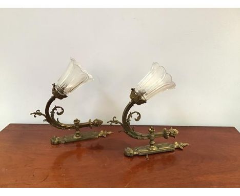 A pair of reproduction brass wall sconces in the Neoclassical taste with foliate plate and scroll branch surmounted by an aco