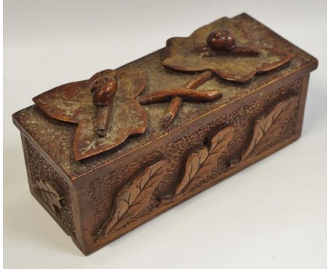 An Arts &amp; Crafts carved oak tea caddy surmounted with carved ivy leaves and snail details, hinged cover revealing storage