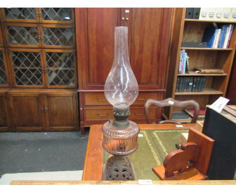 A Victorian cast iron based oil lamp with light pink ribbed design glass reservoir and chimney