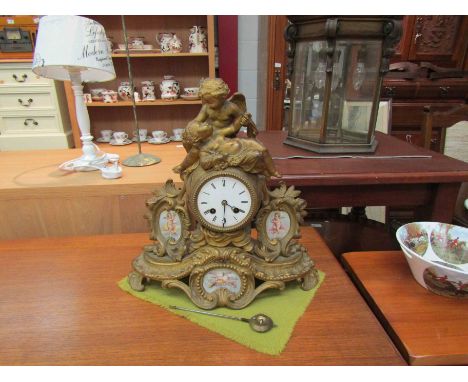 An ornate gilt clock with cherubic design, painted scenes of cherubs