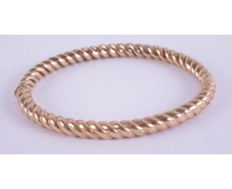 A 9ct yellow gold and twist hinge bangle, approximately 14.2g.