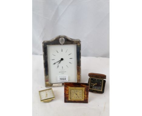 Three travelling timepieces and a desk clock in plated frame with Royal Thames Yacht Club crest 