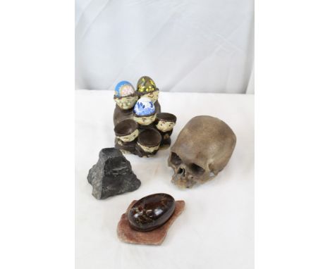 Old ceramic human skull, novelty monk egg holder, polished hardstone egg and two stands
