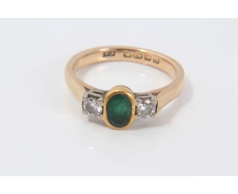 Ladies gold (18ct) ring, the central oval cut emerald flanked by two brilliant cut diamonds in rub-over setting