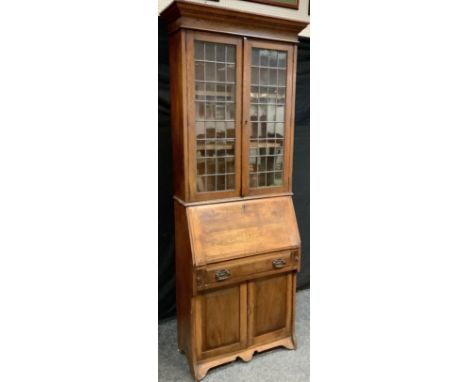 An Arts &amp; Crafts oak bureau bookcase, outswept cornice above a pair of astragal cupboard doors enclosing two adjustable s