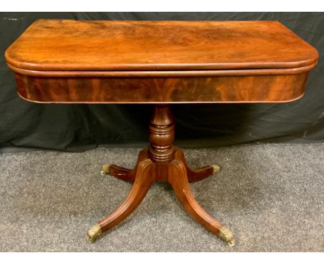 A Regency style Victorian mahogany card table, folding top rounded rectangular top above a turned column, sabre legs, brass p