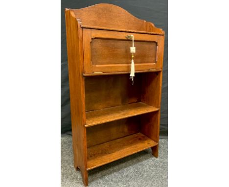 An Arts and Crafts period oak bookcase cabinet of small proportions, arched pediment, small drop down cabinet door to top, ab