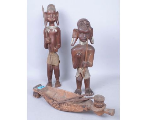 TRIBAL INTEREST, A PAIR OF EARLY 20TH CENTURY CARVED TRIBAL FIGURES HOLDING SPEARS (3)And a carved hardwood model of a boat.