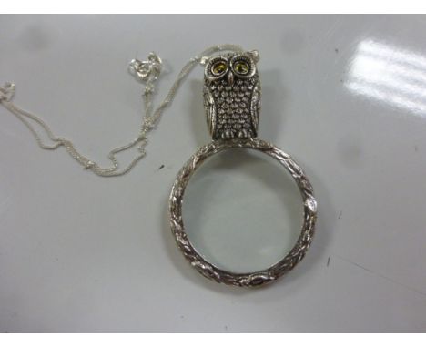 A silver hand held magnifying glass with owl finial on a silver chain 