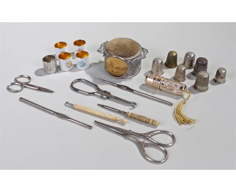 A collection of vintage sewing paraphernalia including a pin cushion, button hooks, thimbles, enamel collars, and scissors, (