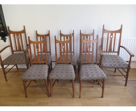 A good set of eight oak Arts and Craft dining chairs including two carvers in the style of Charles Voysey with inverted heart