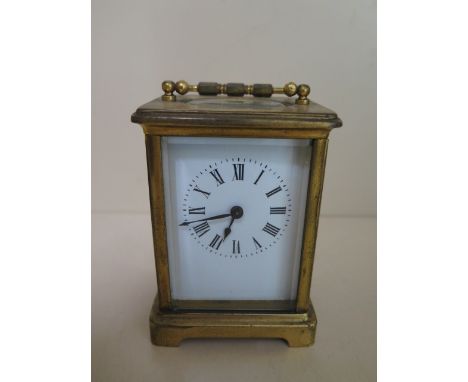 A brass carriage clock, 12cm tall, running, dial good, one small chip to glass door 