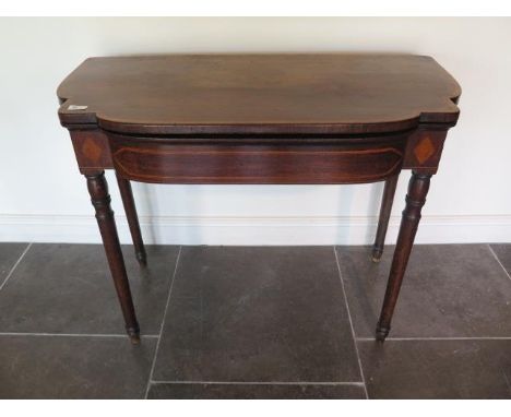 A 19th century mahogany foldover card table with a shaped top on turned legs, 76cm tall x 96cm wide, with some lifting to top