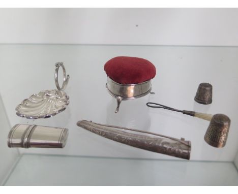 A collection of small silver items, caddy spoon, heart shaped pin cushion, two silver thimbles, a posy holder, needle case an