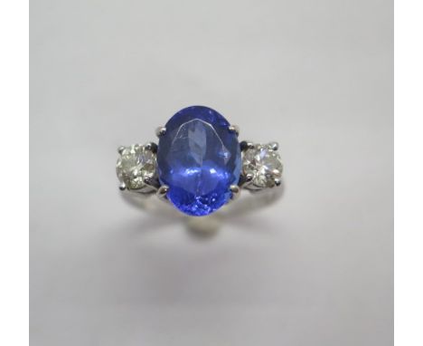 An impressive 18ct white gold tanzanite and diamond three stone ring on a plain band, the centre tanzanite approx 6.4ct with 