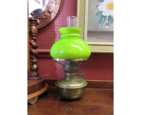 A brass oil lamp with chimney and green glass shade