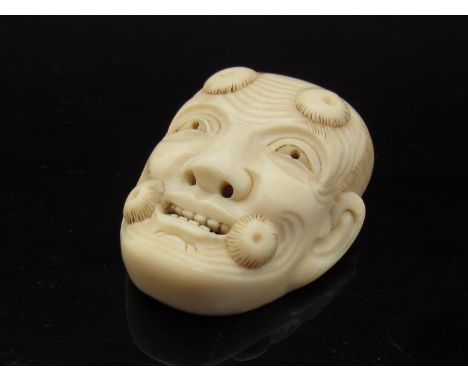 A 19th Century noh-mask ivory netsuke with signature to reverse, 4.5cm long, chip to reverse