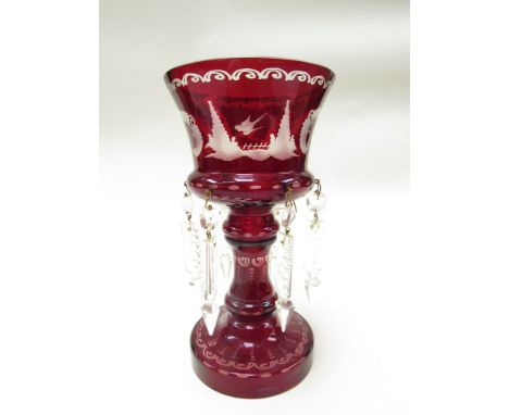 A pair of ornate gilt candlesticks, faceted ruby glass stems to spreading bases with lizard and foliage decoration on scroll 