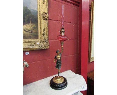 An Art Deco figural oil lamp with cranberry font complete with chimney, 76cm tall
