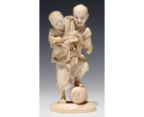 A JAPANESE IVORY OKIMONO OF A STREET VENDOR AND HIS SMALL SON, THE MAN'S FOOT RESTING ON A FESTIVAL DRUM, 11.5CM H, SIGNED ON