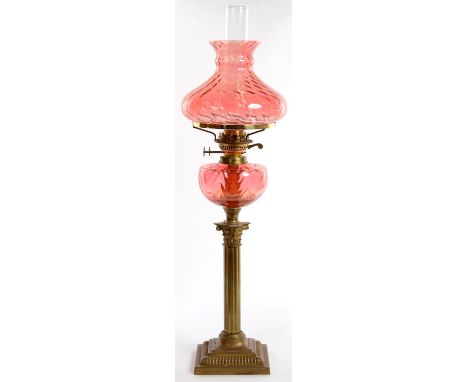 A BRASS COLUMNAR OIL LAMP WITH CRANBERRY GLASS FOUNT AND BRASS BURNER, CONFORMING SHADE, 73CM H EXCLUDING CHIMNEY  