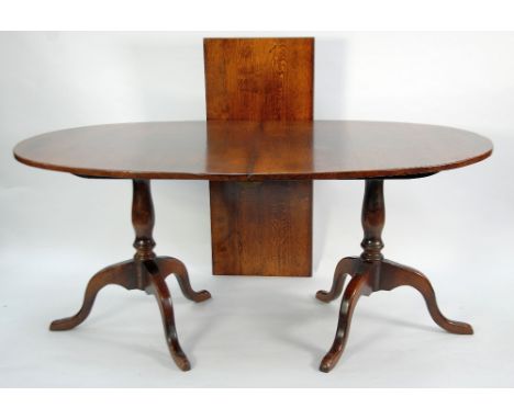 BATHEASTON REPRODUCTION OAK TWIN PEDESTAL DINING TABLE WITH EXTRA LEAF, the solid oval top raised on vase shaped columns and 