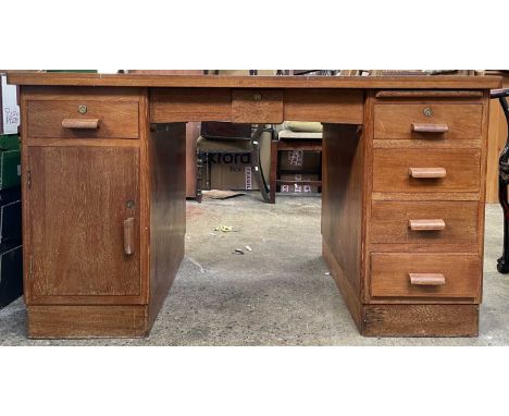 A teak pedestal desk, fitted with an arrangement of six drawers and a cupboard. Height 75cm, width 137.5cm, depth 76cm.