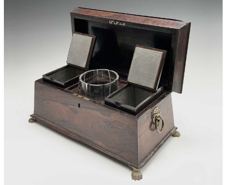 A Regency rosewood tea caddy, of sarcophagus shape, with a glass mixing bowl and two lidded containers, brass lion mask handl