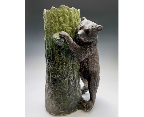 A Bretby pottery stick stand, circa 1900, modelled as a brown bear with inset glass eyes standing beside a green glazed tree 