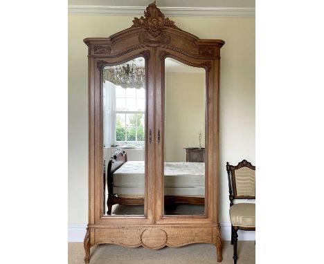 A French walnut armoire, late 19th century, with carved decoration, the two mirror doors enclosing a shelf, hanging space and