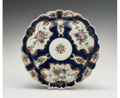 A Worcester porcelain plate, circa 1770, the blue scale ground decorated with gilt edged floral panels, W script mark, diamet