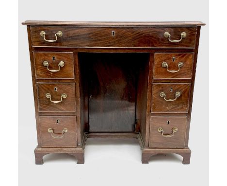 A George III mahogany kneehole desk, with a single frieze drawer above six drawers flanking a cupboard door, on bracket feet.