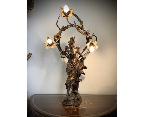 A French Art Nouveau gilt spelter table lamp, modelled as a lady standing on a foliate base, the leaf sprigged wreath fitted 