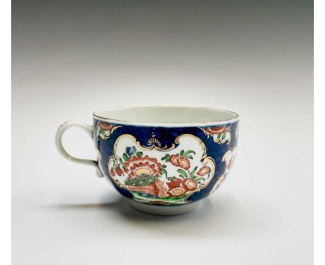 A Worcester porcelain teacup and saucer, circa 1770, the blue scale ground decorated with panels of Japan flowers, blue seal 