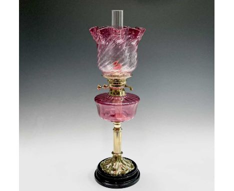 A Victorian cranberry glass and brass oil lamp, with spiral fluted shade and column support, overall height 64cm.Condition re